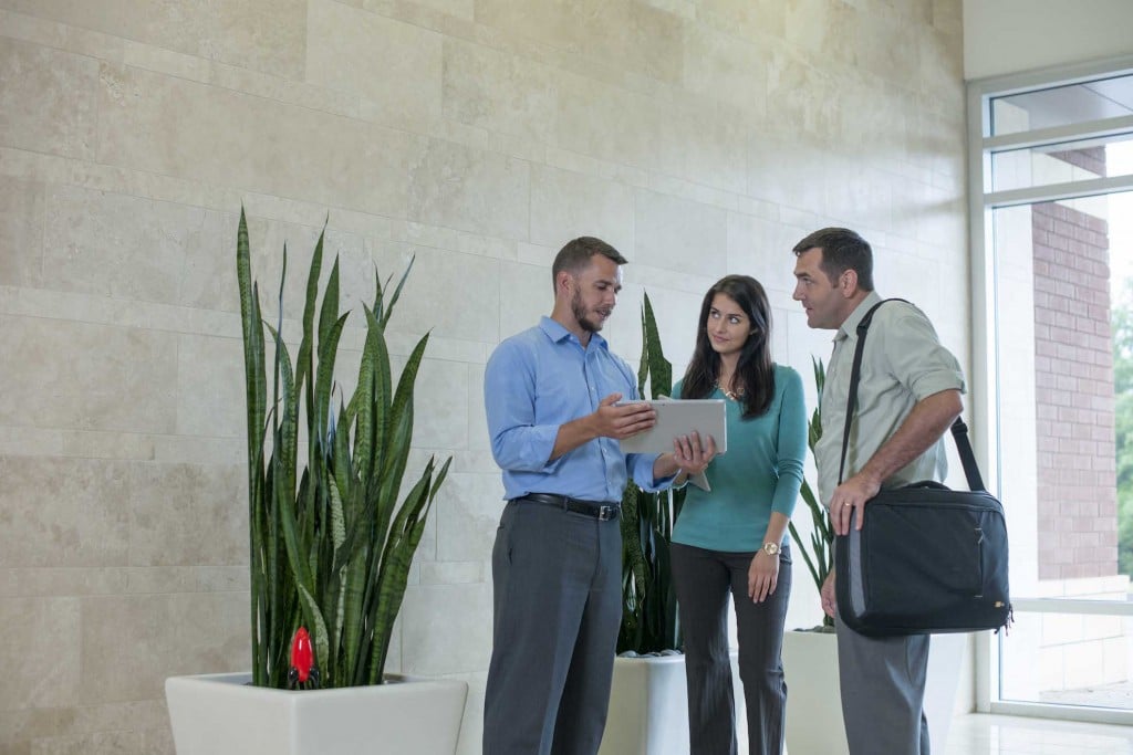 Ryan Bonilla and tech team reviewinga tablet device report in an open office lobby