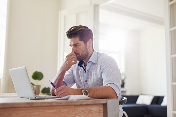 Man thinking at his desk with a computer and papers