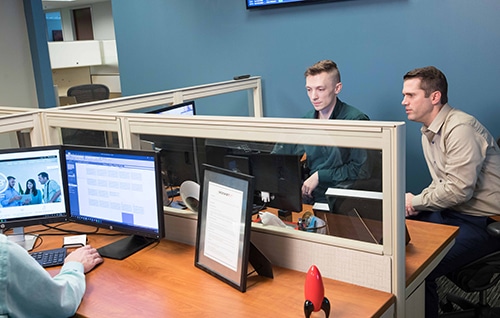 technology staff working together at a computer desk in an office